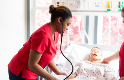 A nursing student at New England College takes a patient's blood pressure in the nursing lab.