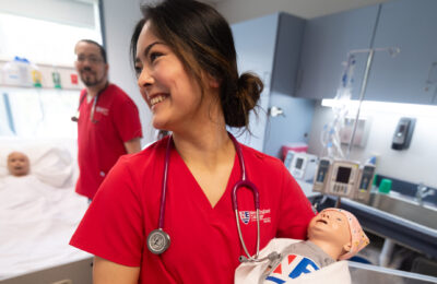 Student in New England College's three-year "earn while you learn" BSN program practices her nursing skills in the nursing lab.