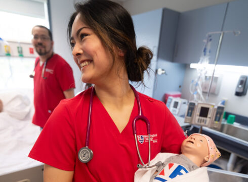 Student in New England College's three-year "earn while you learn" BSN program practices her nursing skills in the nursing lab.