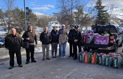 Faculty, students, and local police photographed with toys donated during New England College's Criminal Justice Club 2024 toy drive to benefit patients at Children's Hospital at Dartmouth