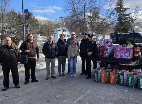 Faculty, students, and local police photographed with toys donated during New England College's Criminal Justice Club 2024 toy drive to benefit patients at Children's Hospital at Dartmouth