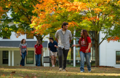 smiling students walking by NEC sign