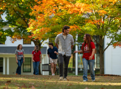 smiling students walking by NEC sign