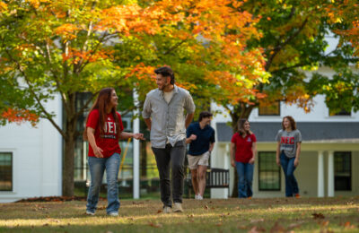 smiling students walking by NEC sign