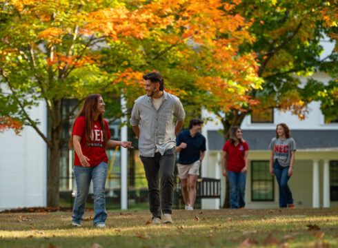 smiling students walking by NEC sign